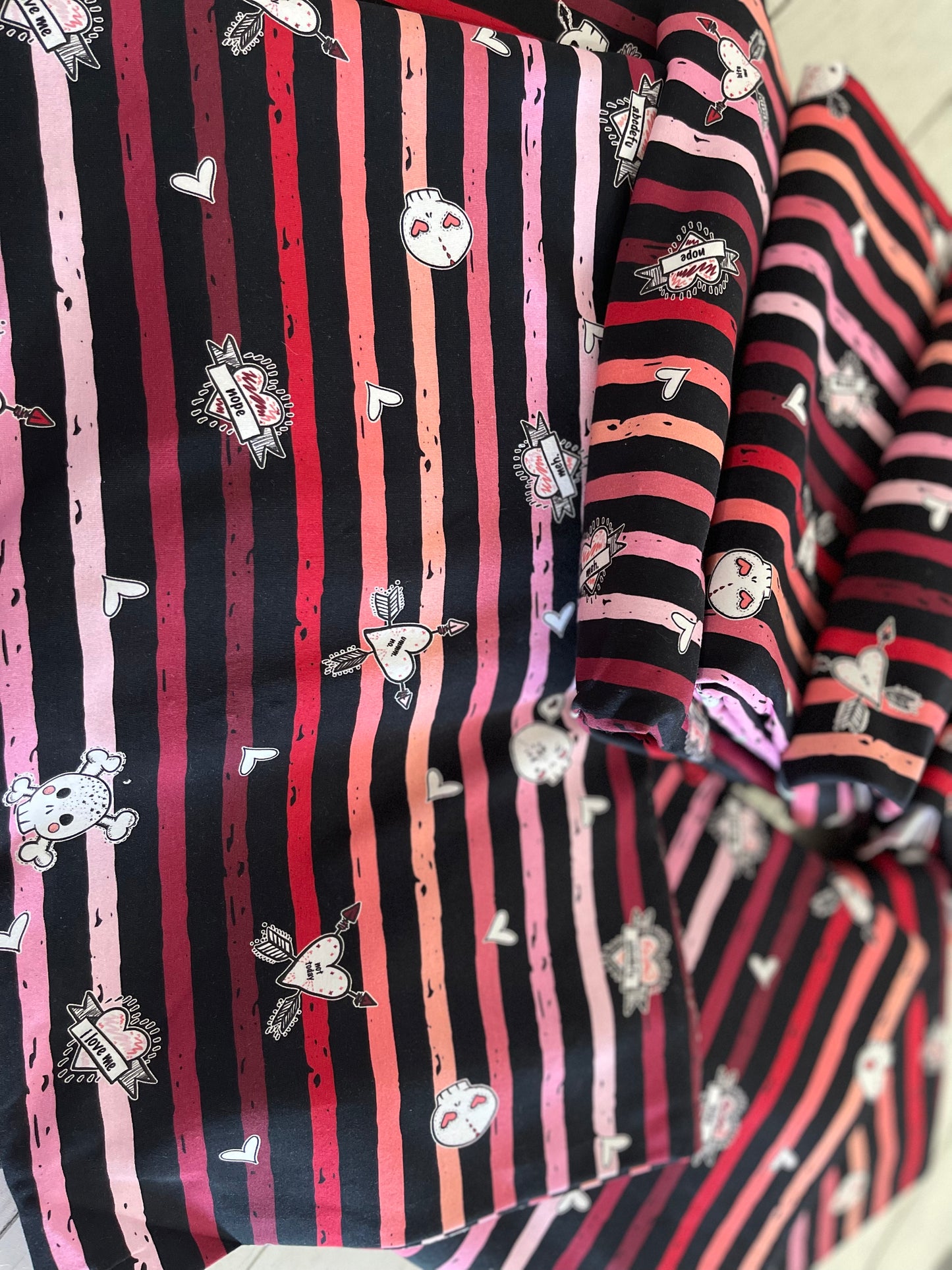 A piece of fabric with pink and black stripes and a skull pattern.